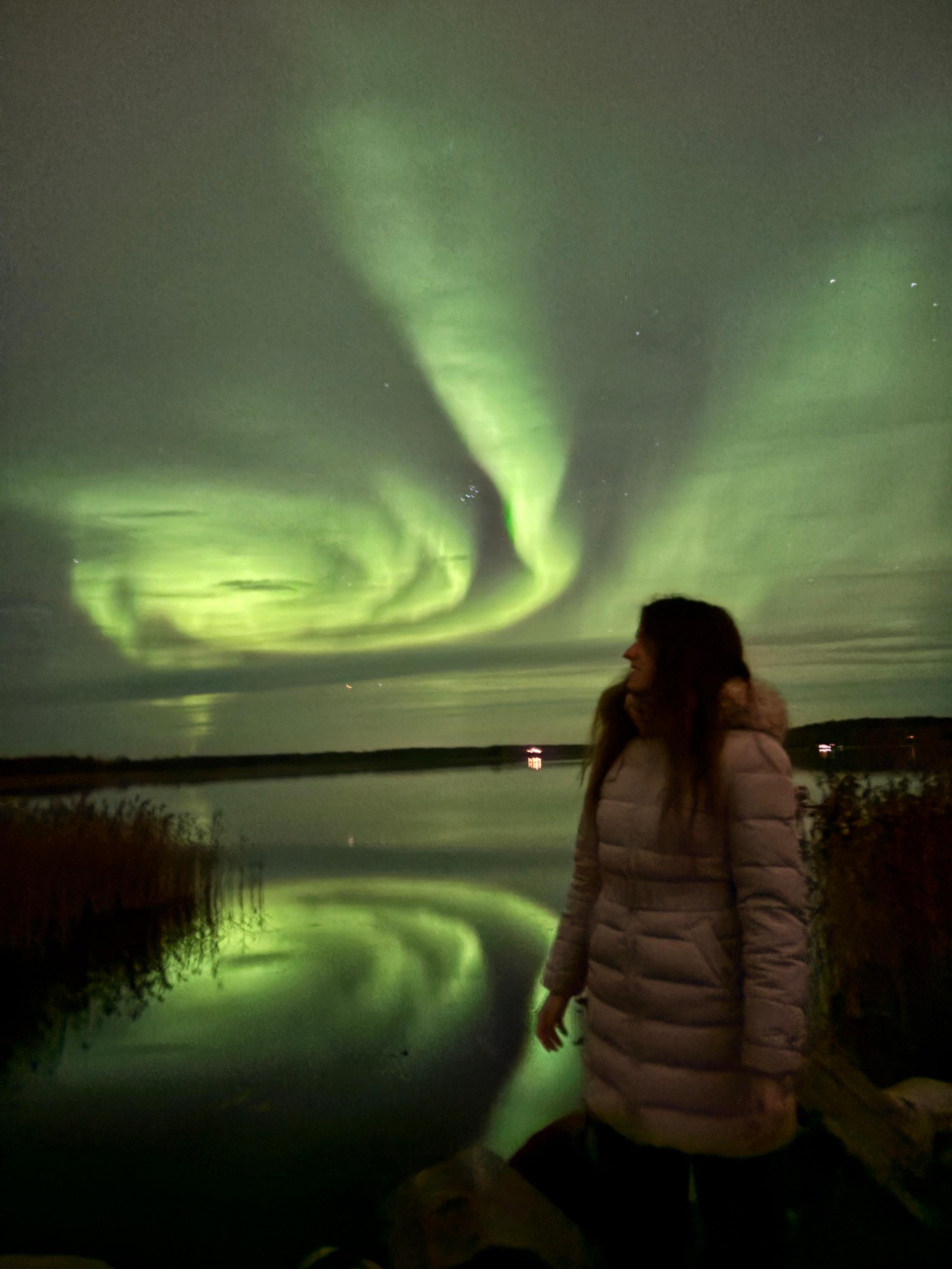 La autora de la guía mirando la aurora boreal junto a un lago en Rovaniemi